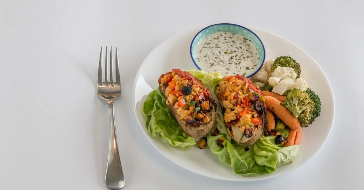 Plat végétarien délicieux avec des pommes de terre farcies, des légumes frais et un accompagnement de sauce crémeuse.
