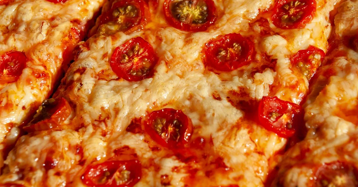 Gros plan d'une pizza italienne au fromage garnie de tomates cerises fraîches, parfaite pour les gourmands.