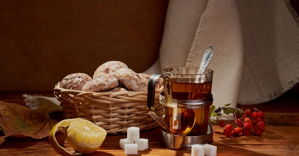 Nature morte chaleureuse représentant du thé, des biscuits au pain d'épice, du citron, des morceaux de sucre et des baies.