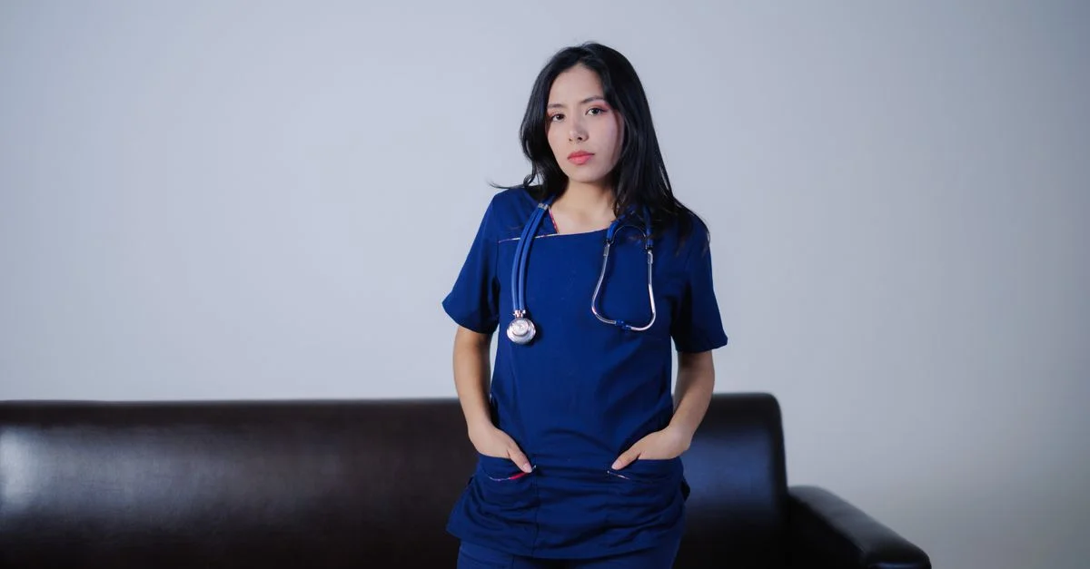 Une jeune infirmière se tient avec confiance à l'intérieur avec un stéthoscope, faisant preuve de professionnalisme et de soin.