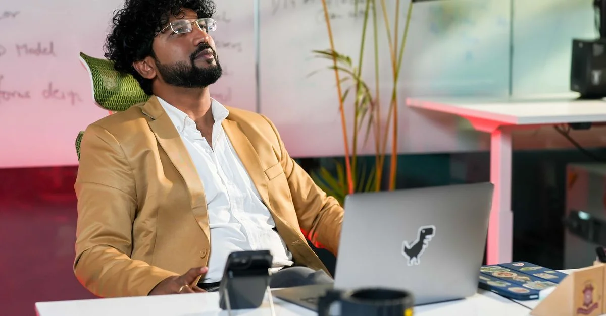 Un homme d'affaires dans un bureau moderne, prenant une pause avec une tasse de café et son ordinateur portable.