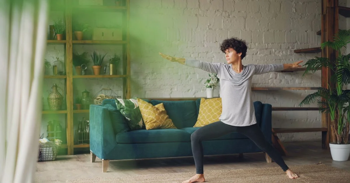 Jeune femme pratiquant une posture de yoga dans un cadre de salon élégant, atmosphère lumineuse et calme.