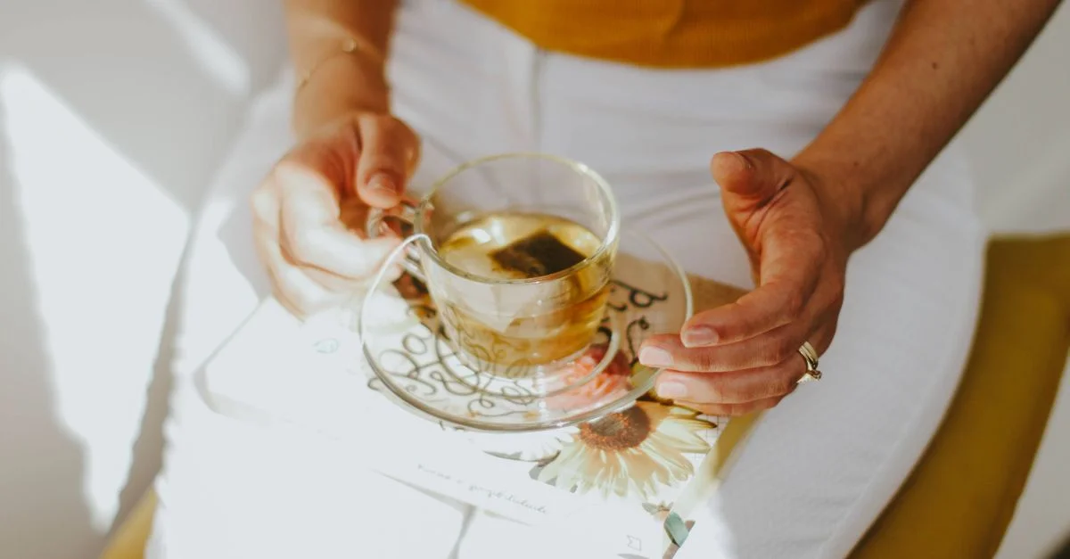Une scène sereine d'une personne savourant une tisane tout en tenant un livre par une journée ensoleillée.
