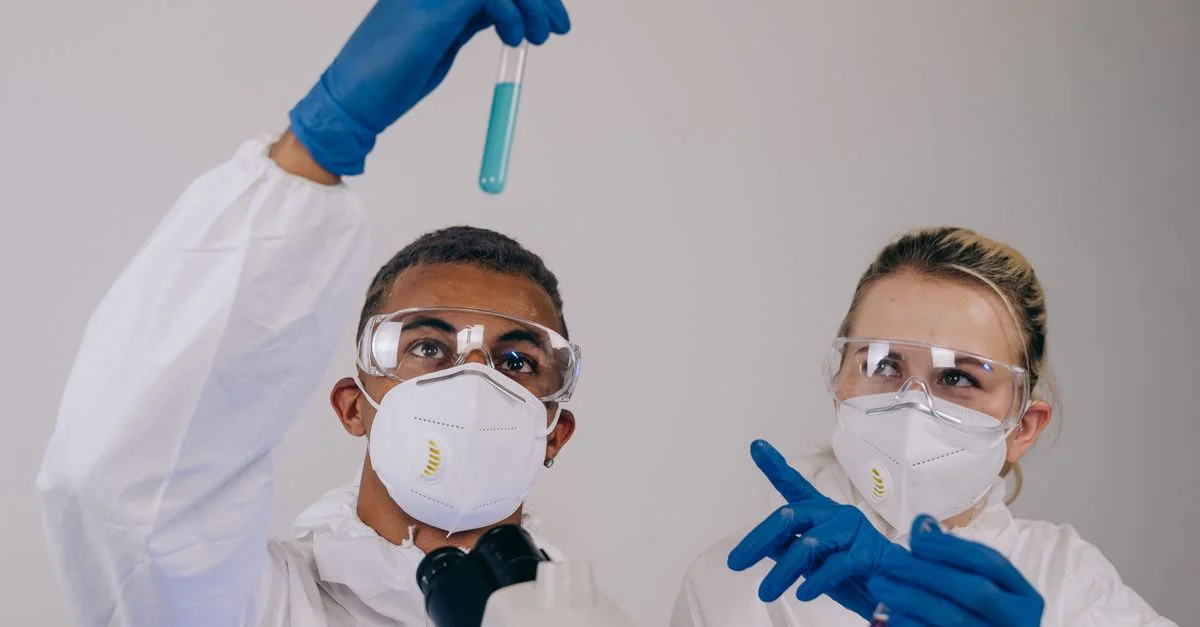 Deux scientifiques en équipement de protection analysant des tubes à essai pour des expériences chimiques dans un laboratoire.
