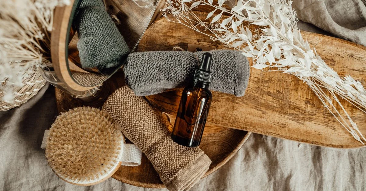Un cadre de spa serein avec de l'huile essentielle, des serviettes, et des fleurs séchées sur un plateau en bois.