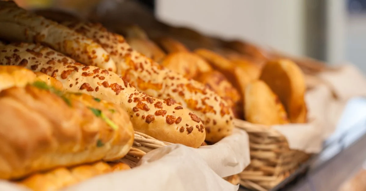 Gros plan sur des pains variés fraîchement cuits dans une vitrine de boulangerie, mettant en avant une variété de textures et de saveurs.