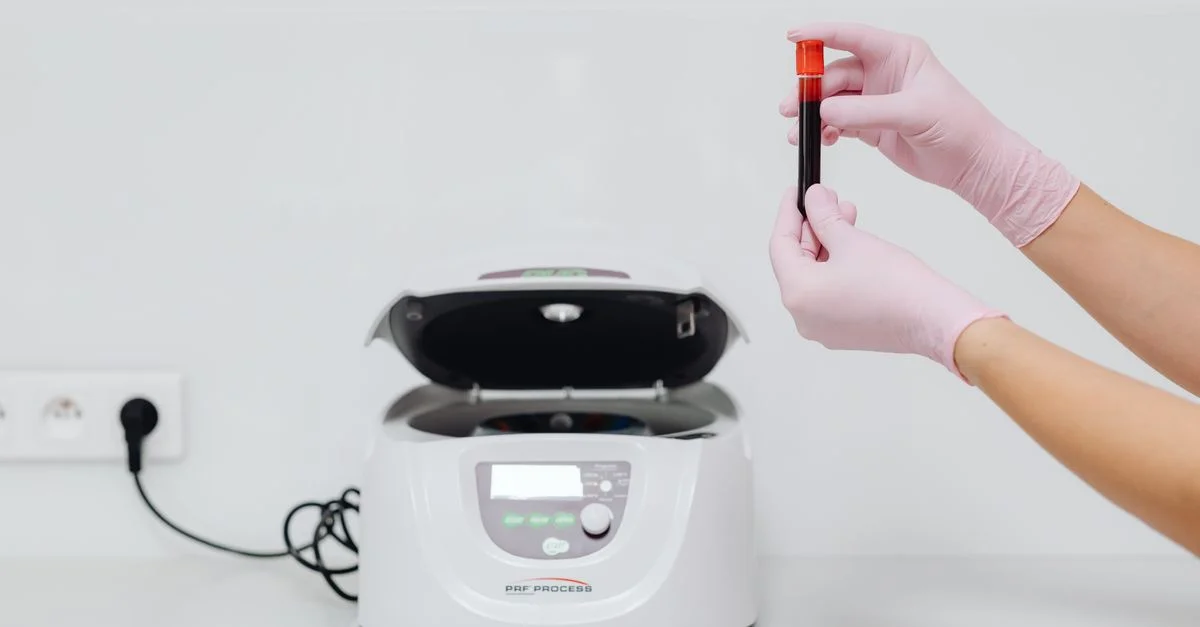 Professionnel de la santé manipulant un échantillon de sang dans une centrifugeuse pour des tests de laboratoire.