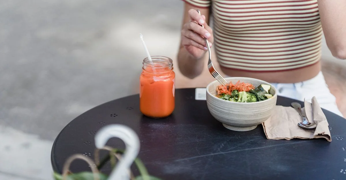 Femme appréciant une salade fraîche et un jus en plein air, promouvant un mode de vie sain.