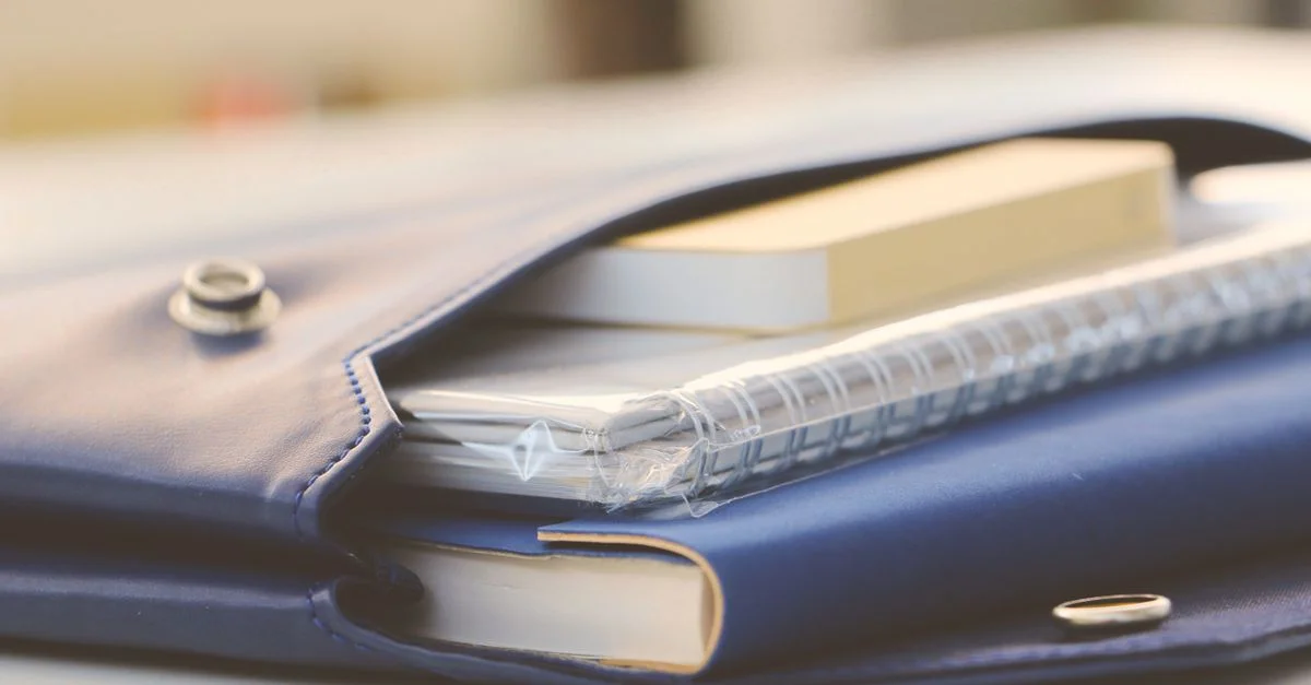 Gros plan d'un élégant portefeuille bleu contenant divers carnets, créant un look de bureau organisé.