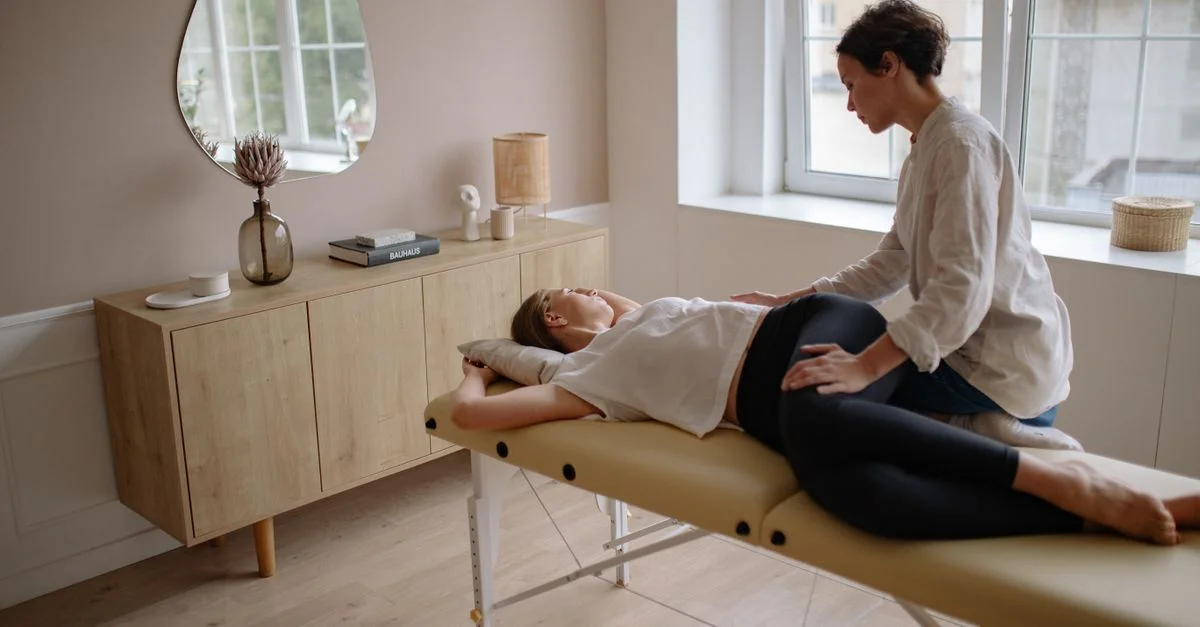 Un thérapeute offre un massage apaisant à une femme allongée sur une table de massage dans une pièce sereine et bien éclairée.