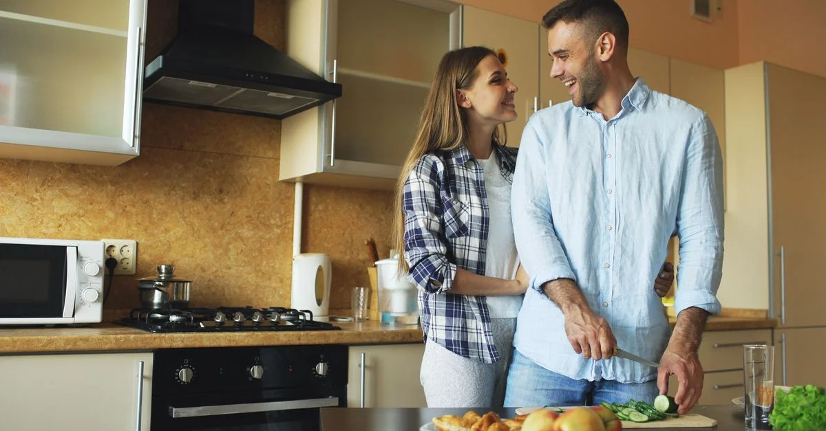Un jeune couple prend plaisir à préparer des repas ensemble dans une cuisine moderne.