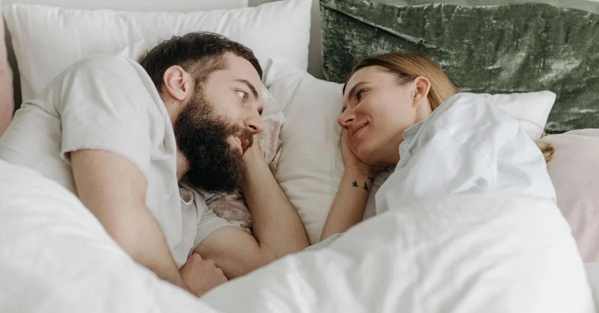 Un couple allongé dans un lit partageant un moment tendre, exprimant l'amour et l'intimité.