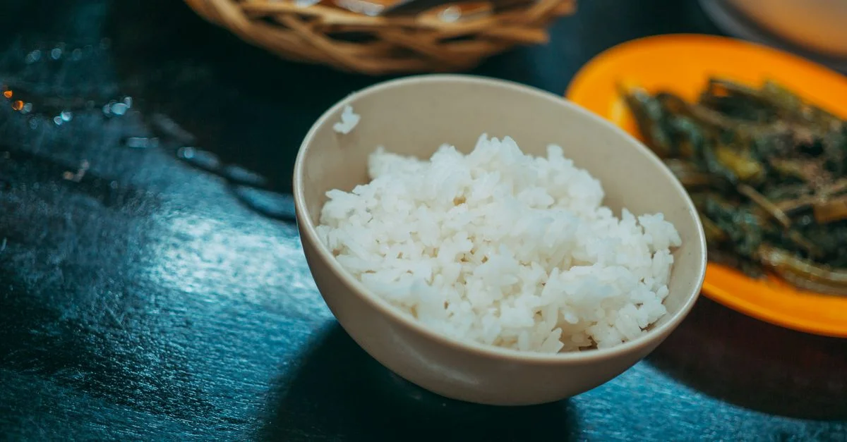 Un gros plan d'un bol de riz blanc avec des légumes sautés à côté, idéal pour les blogs culinaires.