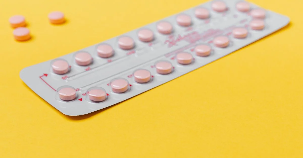 Un blister de pilules roses placé sur un fond jaune vif, symbolisant la médecine et la santé.