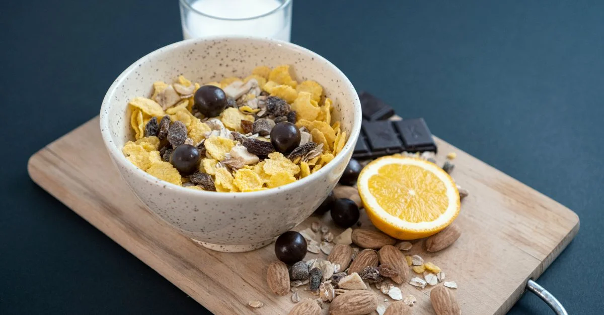 Un bol de granola avec des amandes, des fruits secs et du lait sur une planche à découper pour un petit-déjeuner sain.