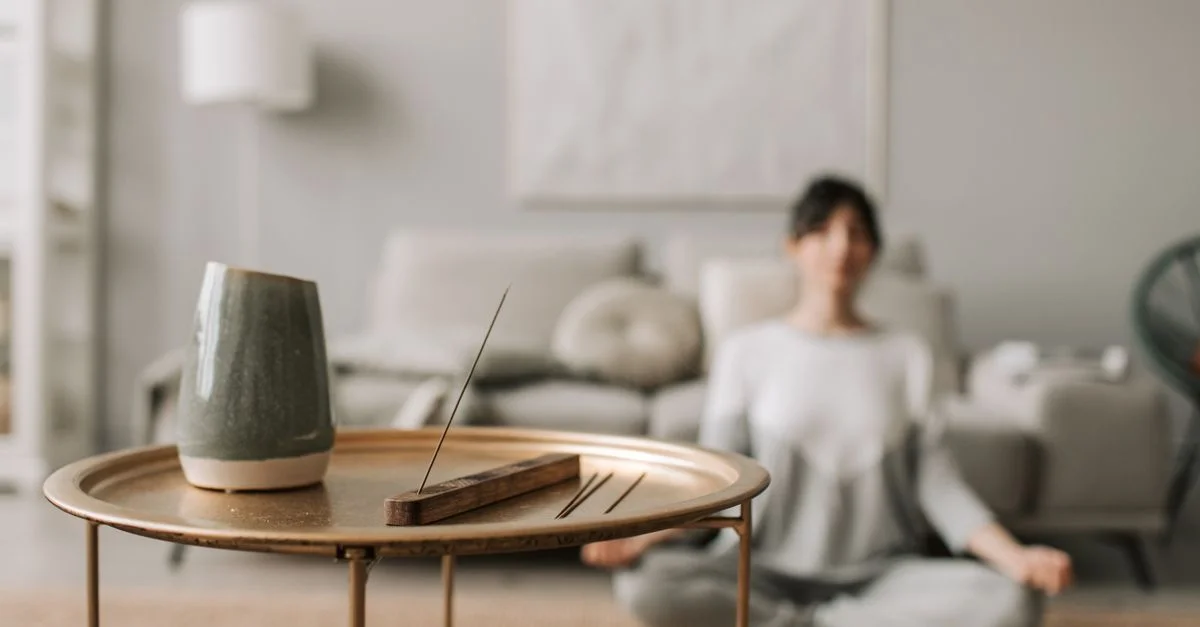 Scène de salon calme avec de l'encens et une femme méditant, parfaite pour des concepts de relaxation.
