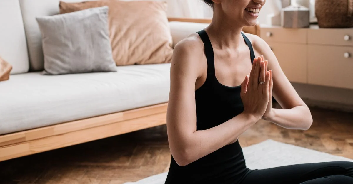 Femme joyeuse méditant dans un cadre intérieur serein, promouvant le bien-être mental et la relaxation.