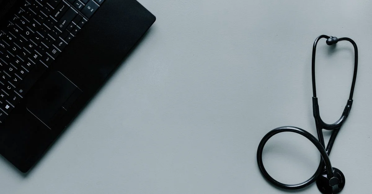 Image minimaliste représentant un ordinateur portable et un stéthoscope symbolisant la télémédecine et la santé numérique.