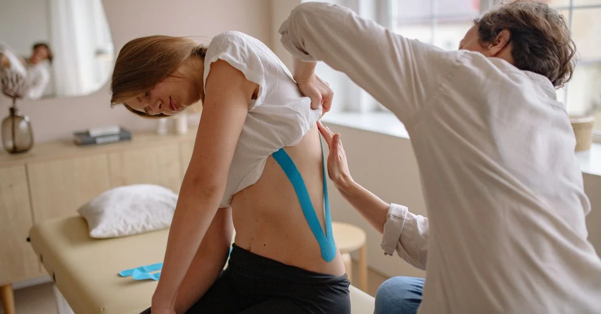 Un chiropracteur utilise du tape kinésiologique pour soulager la douleur au dos d'une femme lors d'une séance de thérapie.