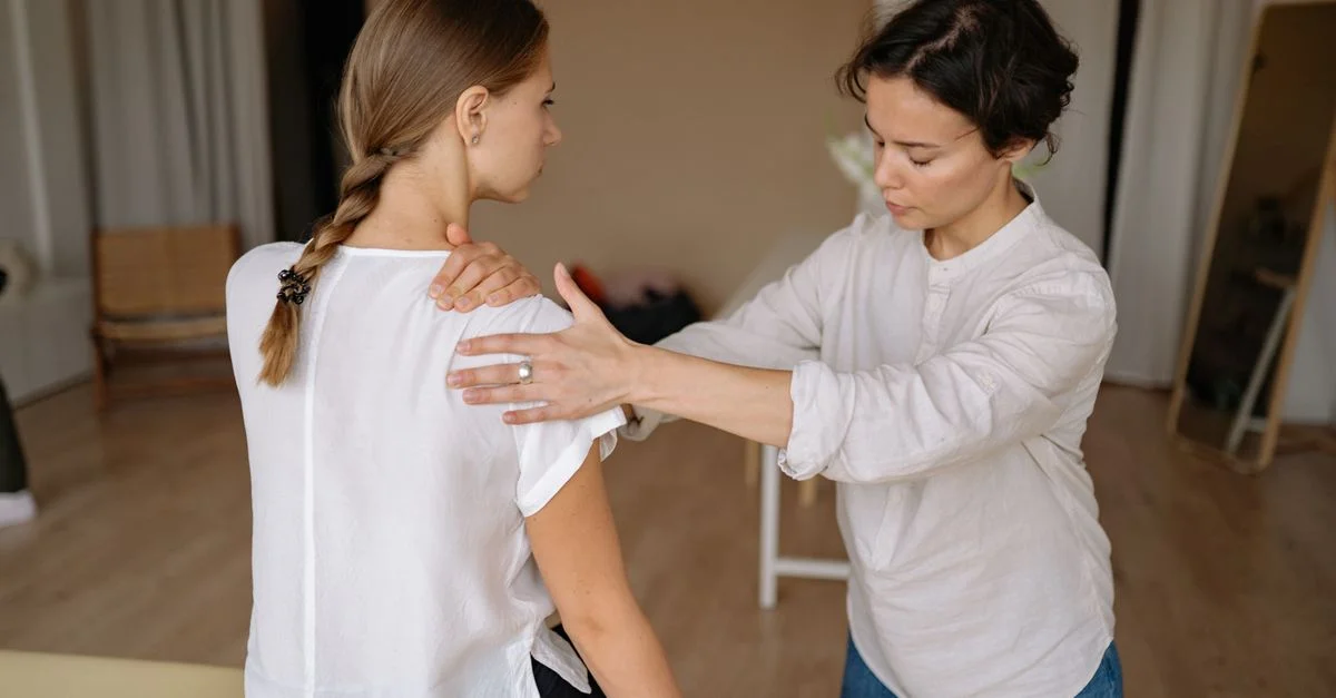 Un thérapeute effectuant un massage de l'épaule sur une femme pour soulager les tensions physiques.