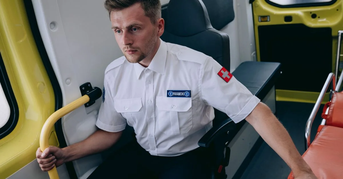 Paramédic concentré en uniforme assis à l'intérieur d'une ambulance, prêt à agir.