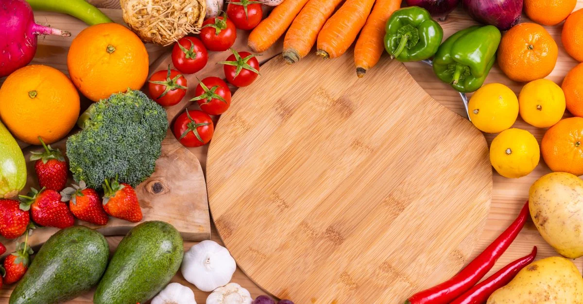 Découvrez un assortiment vibrant de fruits et légumes frais disposés sur une planche en bois. Parfait pour s'inspirer d'une alimentation saine.
