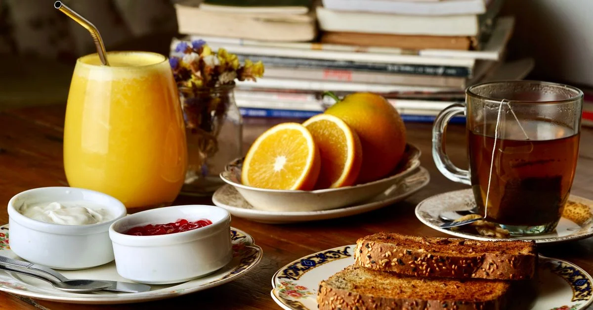 Un petit-déjeuner délicieux et sain avec du jus d'orange, des oranges fraîches, des toasts et du thé.
