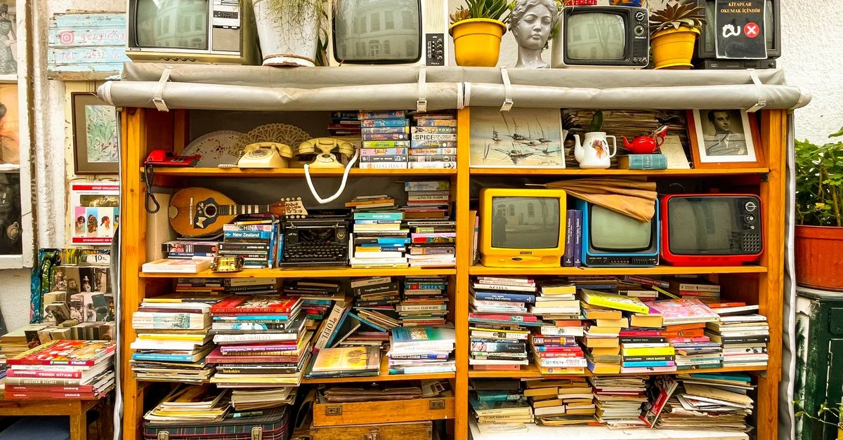Une bibliothèque colorée et éclectique, agrémentée de téléviseurs vintage, de livres et d'objets de décoration originaux, crée une esthétique nostalgique.