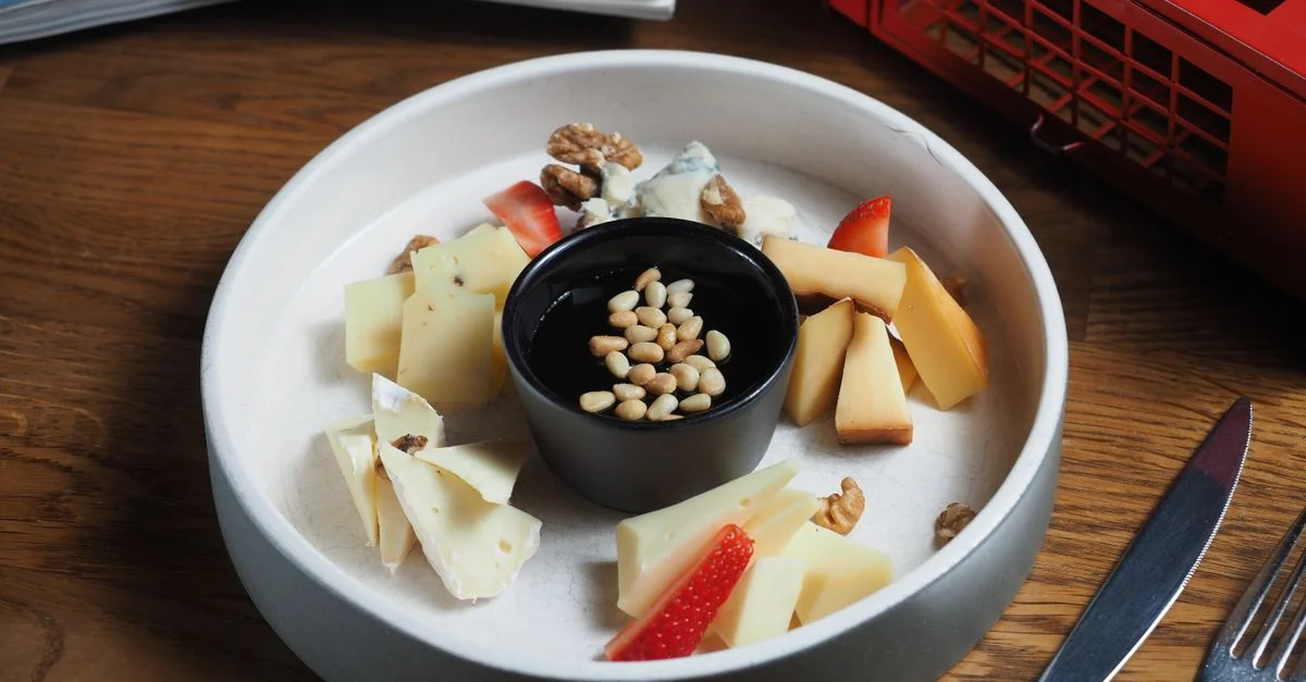 Un plateau de fromage élégant avec divers fromages, noix et fraises sur une table en bois.