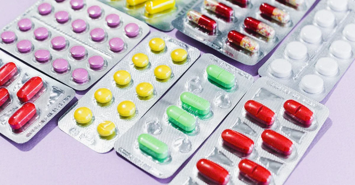 Gros plan sur divers comprimés colorés dans des plaquettes, mettant en avant différents types de médicaments.
