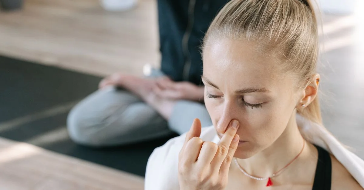 Femme méditant à l'intérieur, pratiquant des techniques de respiration de yoga avec une concentration ciblée.