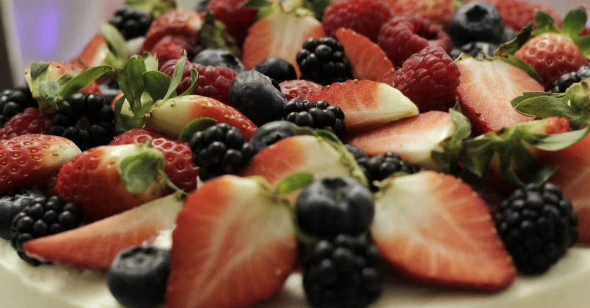Un gros plan vibrant d'un dessert garni de fraises fraîches, framboises, myrtilles et mûres.