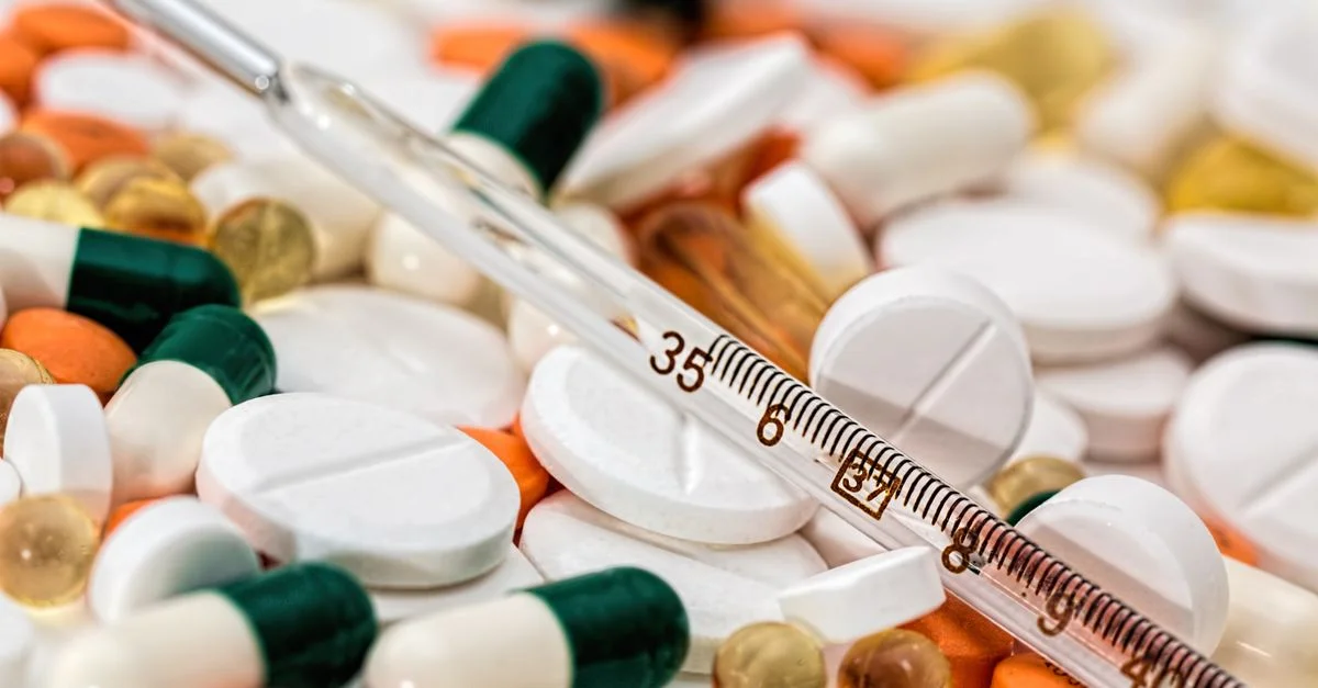 Image en gros plan montrant divers médicaments et un thermomètre, mettant l'accent sur la santé et la médecine.