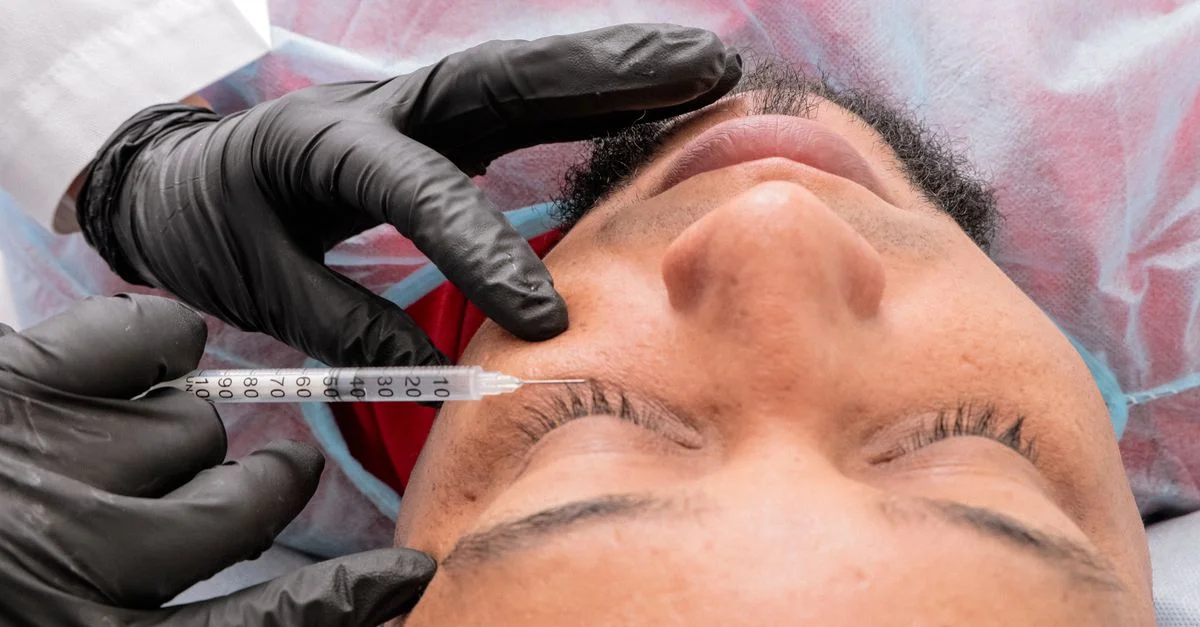 Homme recevant un traitement facial avec une seringue dans un établissement médical.