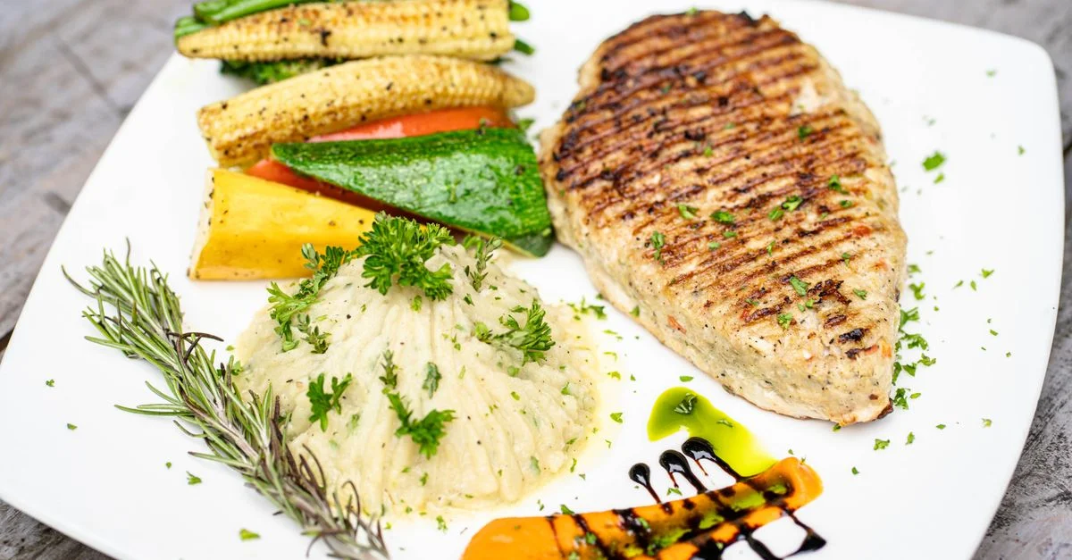 Un délicieux blanc de poulet grillé servi avec de la purée de pommes de terre et des légumes frais.