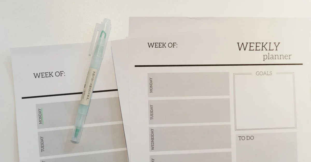 Feuilles de planificateur hebdomadaire organisées avec un stylo pour une planification et un objectif efficaces.