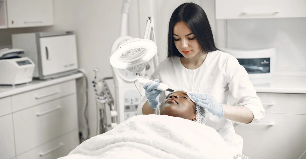 Esthéticienne offrant un soin du visage rajeunissant à une cliente dans un cadre de clinique spa moderne.