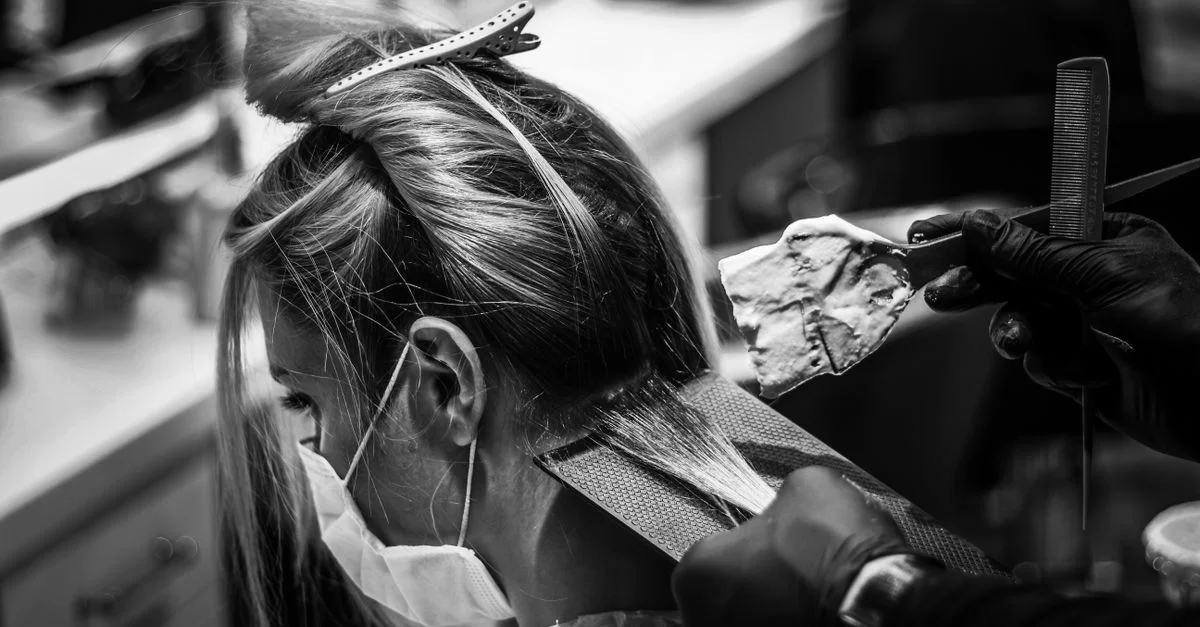 Image monochrome d'une femme se faisant teindre les cheveux dans un salon.