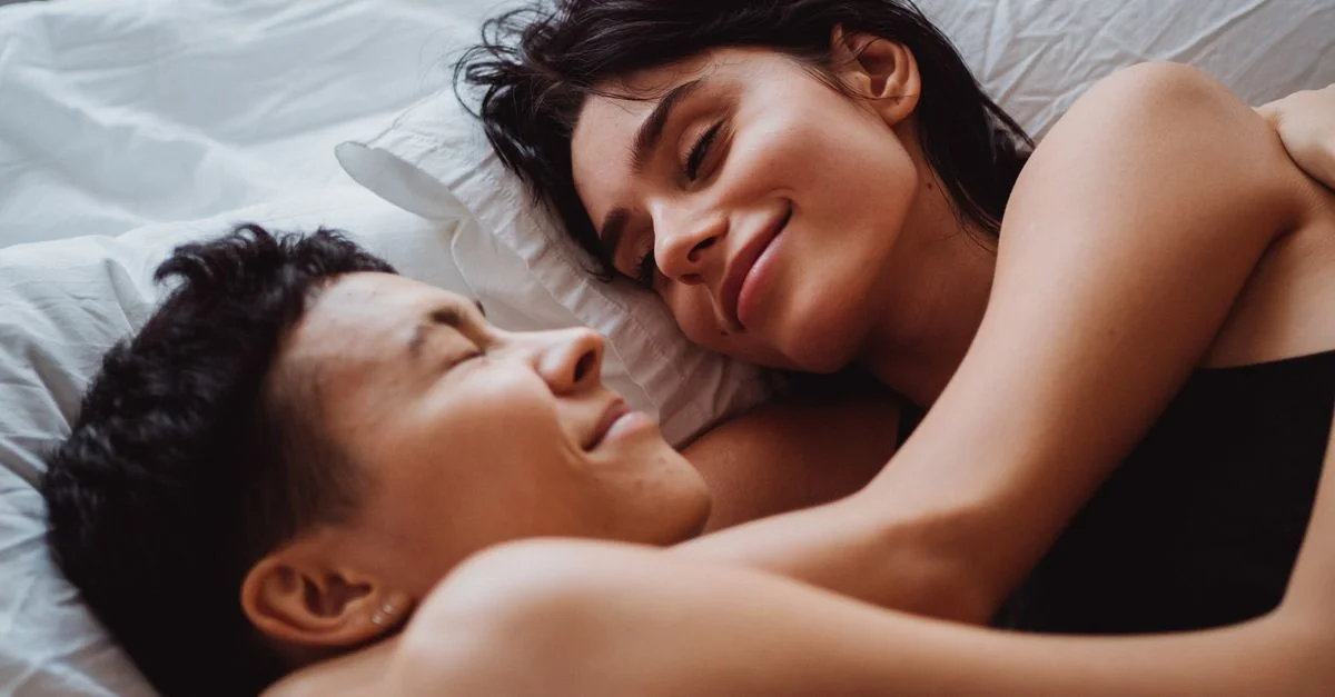Un moment tendre entre un couple aimant de même sexe s'embrassant dans une chambre confortable.