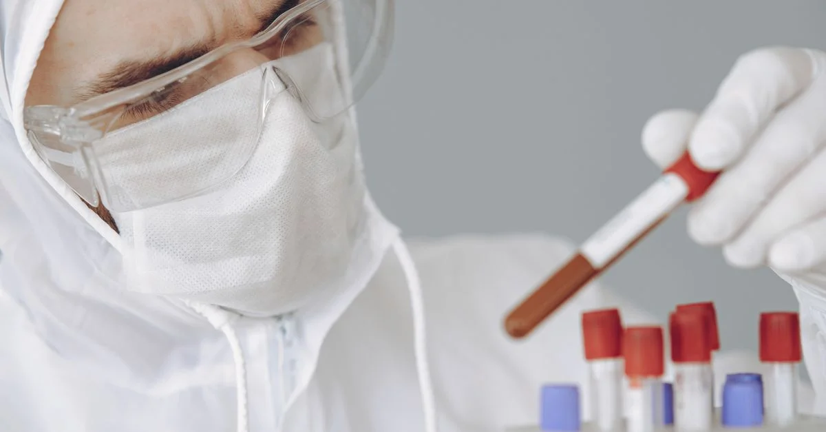 Scientifique en EPI examinant des échantillons dans un laboratoire.