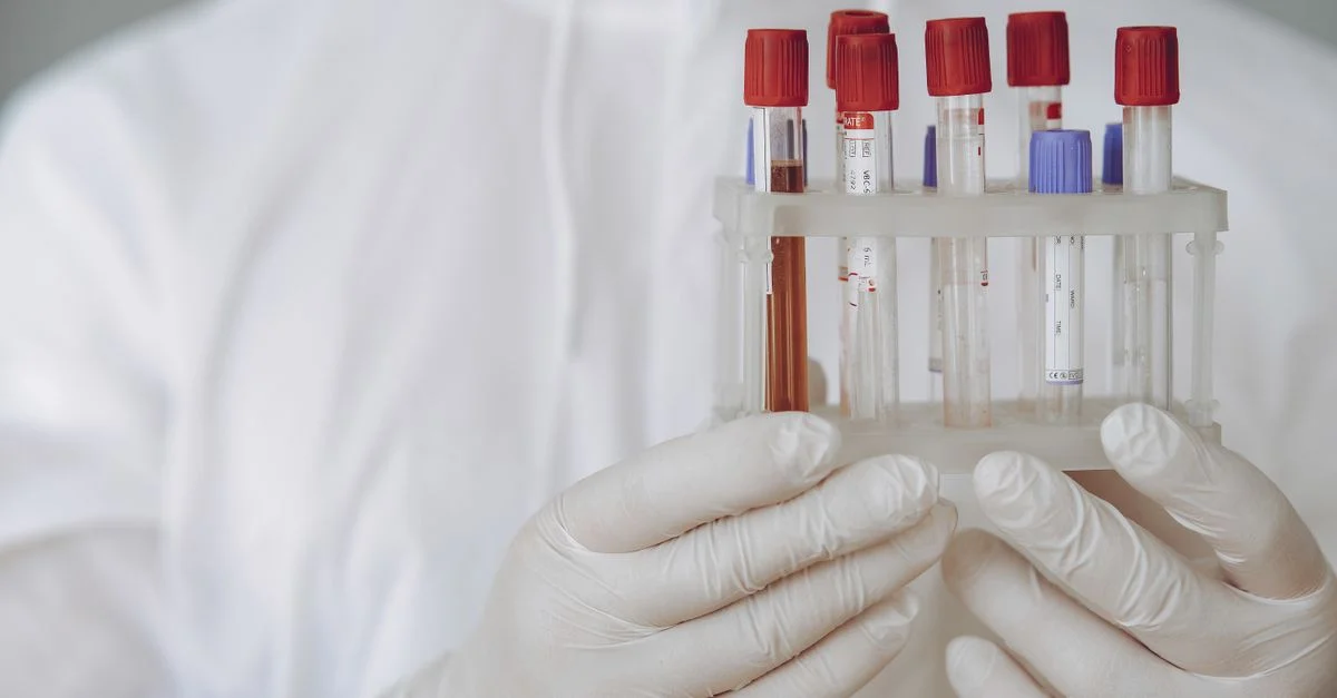 Scientifique en équipement de protection tenant des tubes à essai dans un laboratoire.