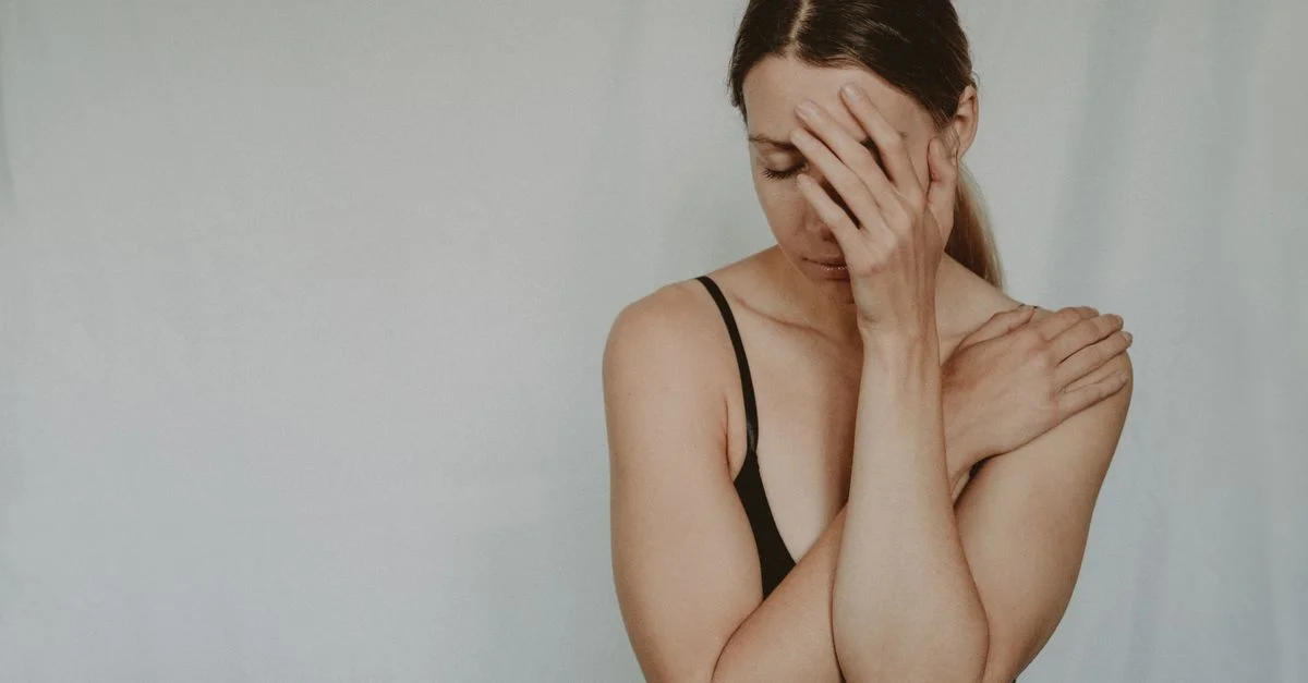 Une femme en contemplation avec une main sur le visage, exprimant une détresse émotionnelle.