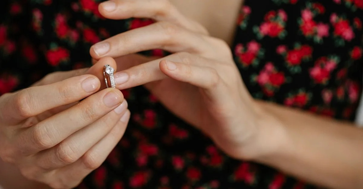 Gros plan sur une femme plaçant une bague en diamant sur son doigt, mettant en valeur l'élégance et le luxe.