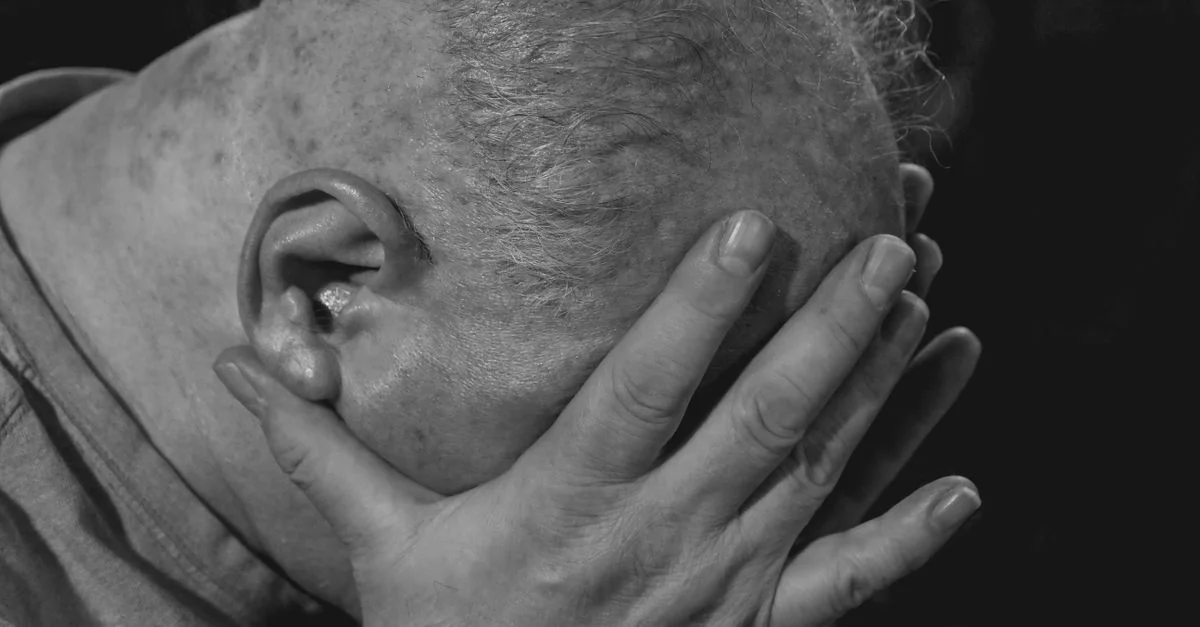 Un gros plan d'un homme âgé en noir et blanc montrant une profonde émotion et de la tristesse.