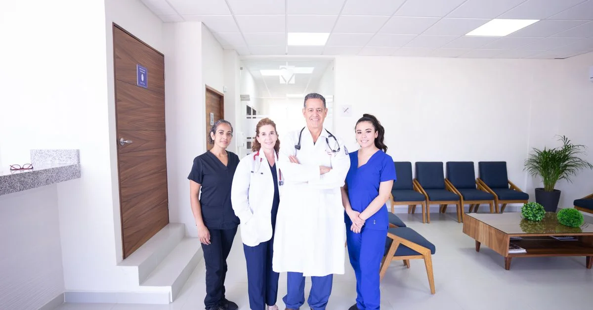 Des praticiens médicaux divers en uniformes, souriant dans une salle d'attente moderne d'hôpital.
