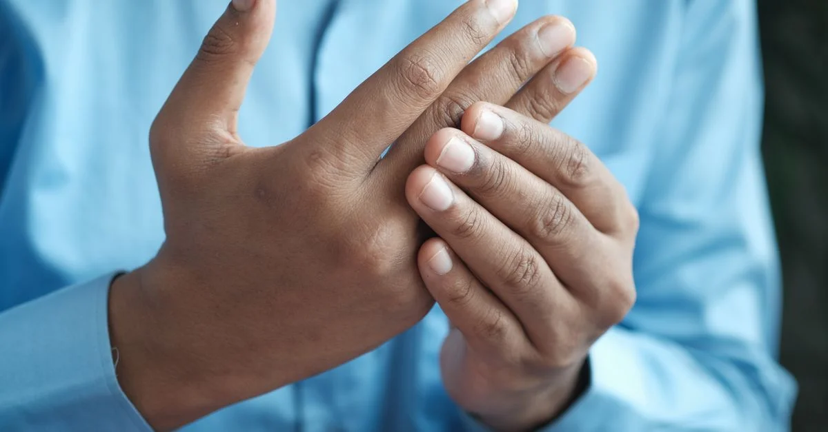 Gros plan d'un homme tenant doucement sa main, symbolisant le confort ou le soulagement de la douleur.
