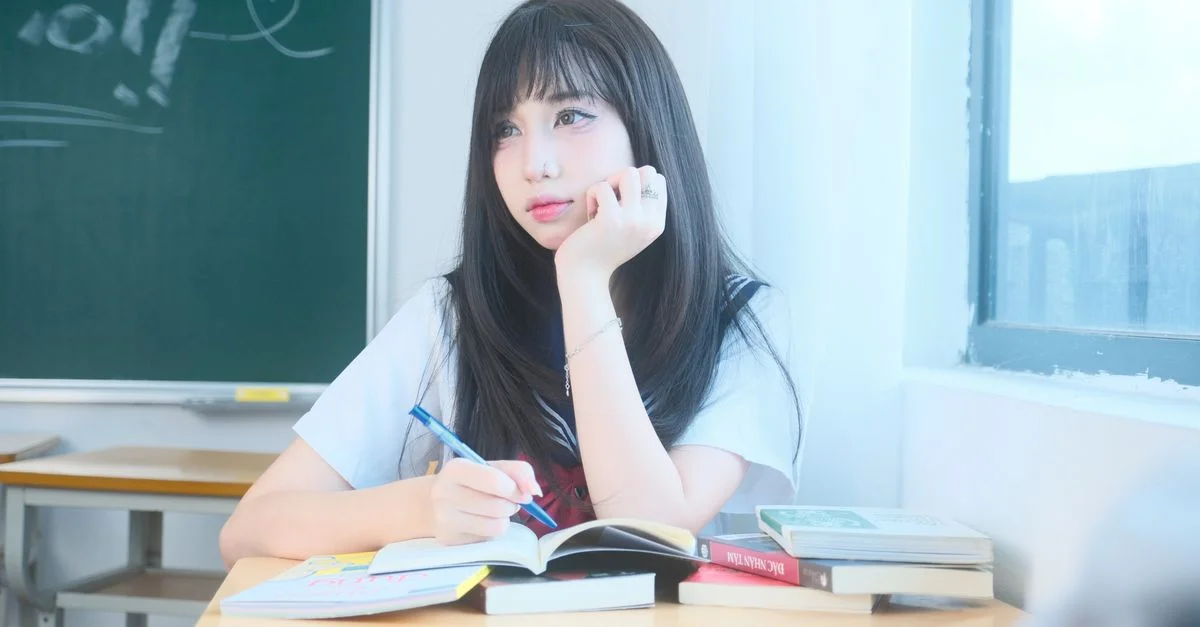 Un jeune étudiant dans une classe vietnamienne regarde pensivement par la fenêtre, entouré de livres.
