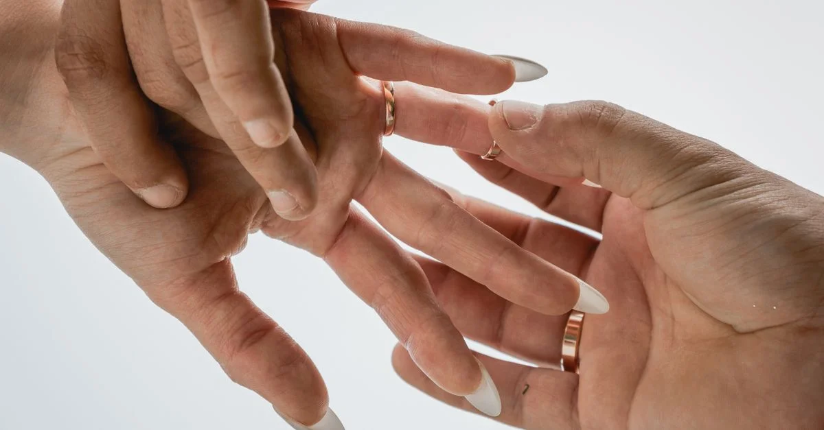 Deux mains d'adultes avec des bagues élégantes, capturées dans une configuration d'éclairage doux, montrant un geste de tendresse.