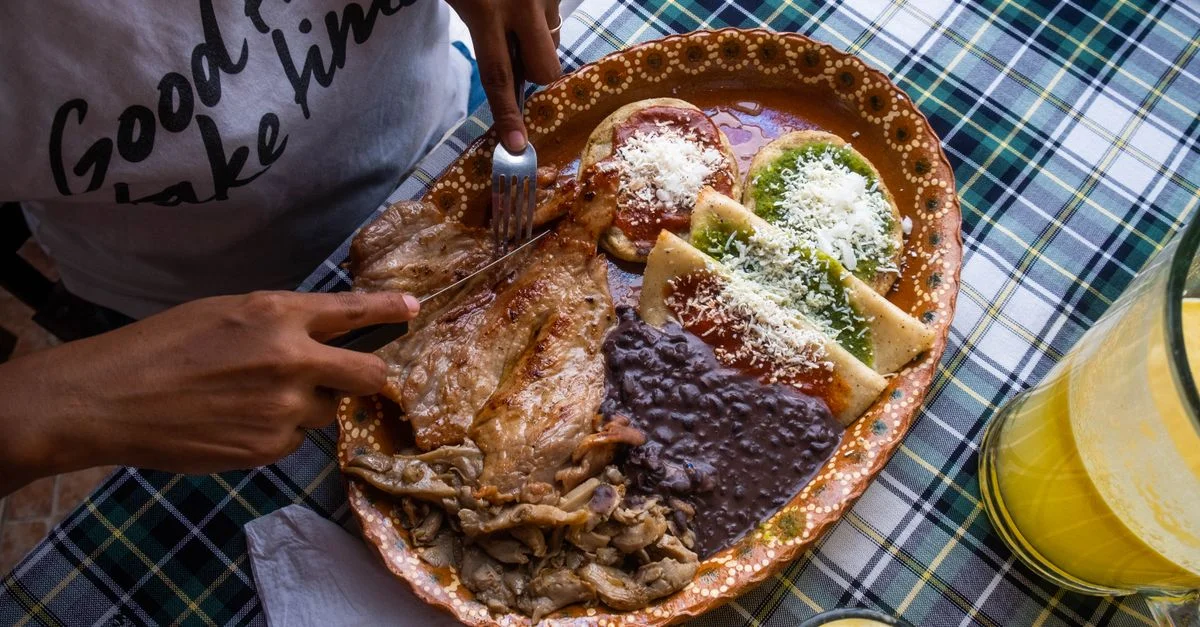 Délicieux plat mexicain traditionnel avec viandes et sauces colorées servi dans une assiette décorative.