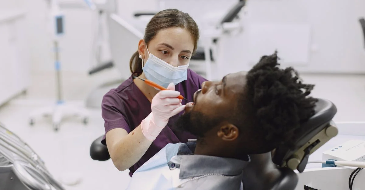 Un dentiste dans une clinique effectuant un contrôle sur un patient avec un bavoir dentaire.